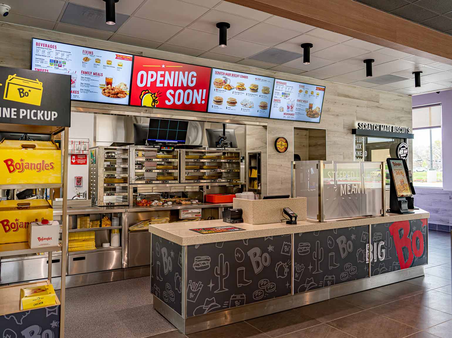 Modern Bojangles restaurant counter with digital menu boards, pickup station, and open kitchen service area.