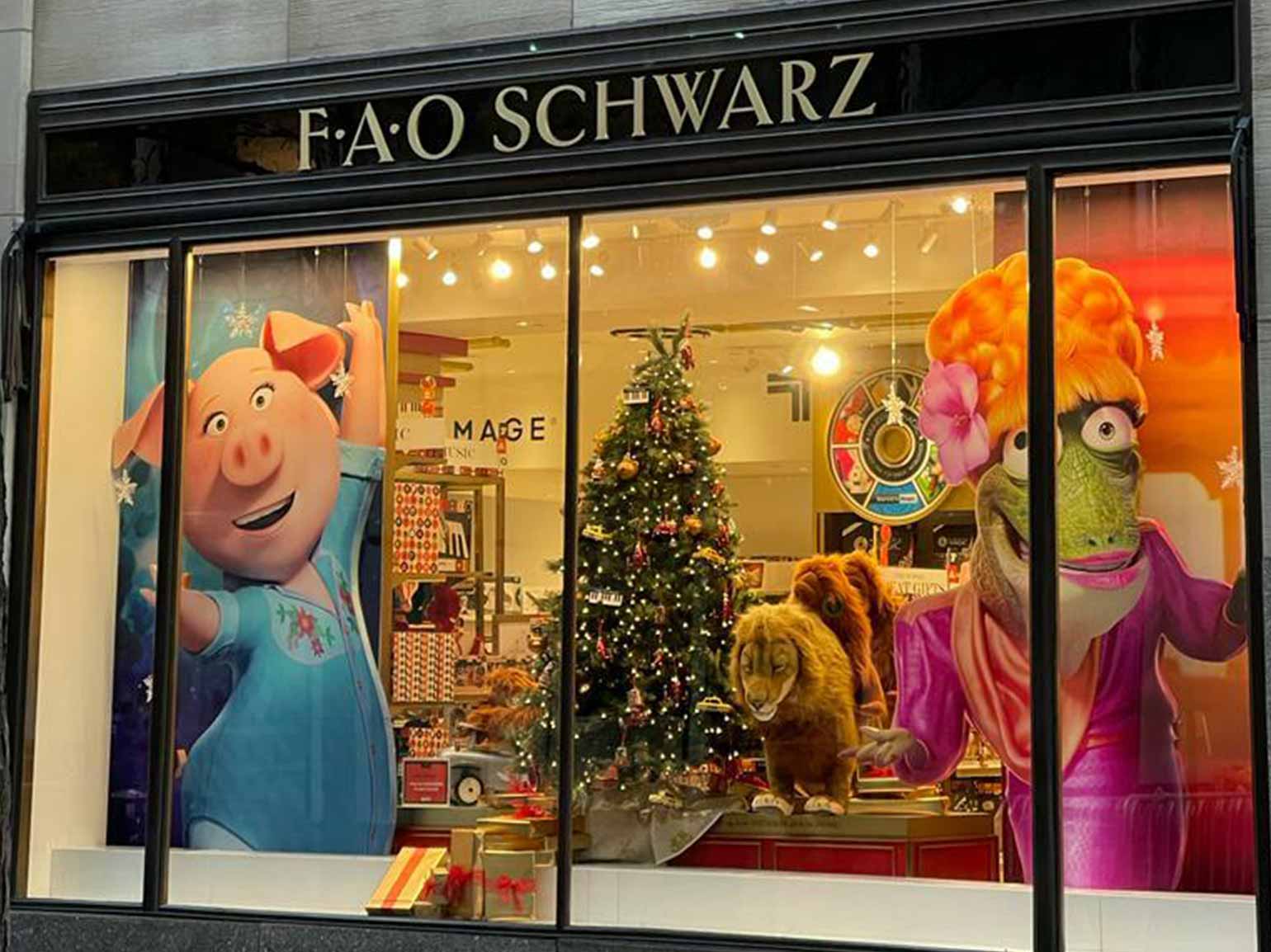 FAO Schwarz holiday window display featuring Sing 2 characters, festive decorations, and a Christmas tree.