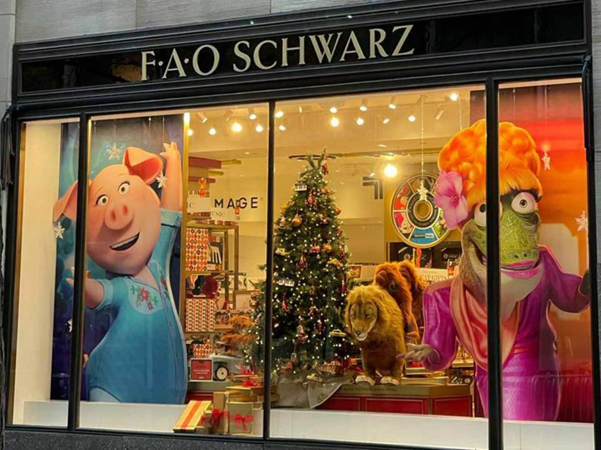 FAO Schwarz holiday window display featuring Sing 2 characters, festive decorations, and a Christmas tree.